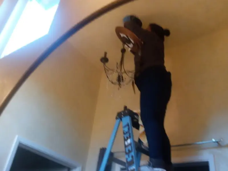 Electrician installing a chandelier in a Durham residence